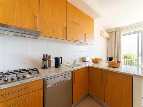 a kitchen with wooden cabinets and a sink at An Idyllic Algarve Home by the Water in Fuzeta