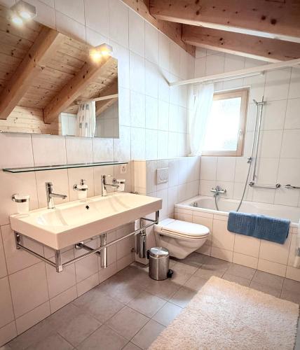 a white bathroom with a sink and a toilet at Chalet Poiema in Bellwald