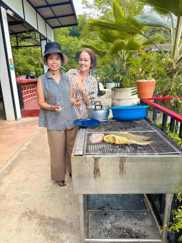 two women standing next to a grill with food on it at Lake View Resort in Ban Nam Rop
