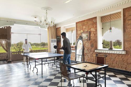 two men standing in a room with ping pong tables at SaffronStays Raj Reverie in Jaipur