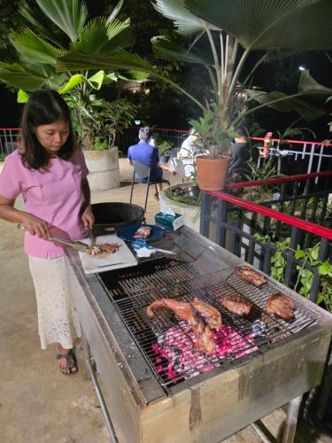 a woman is cooking meat on a grill at Lake View Resort in Ban Nam Rop