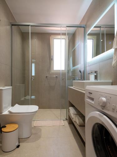 a bathroom with a shower toilet and a washing machine at Karmis - Gournes NewTown Residences in Gournes