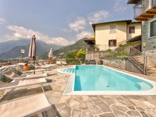 a pool with chairs and an umbrella next to a building at Wonderful flat with swimming pool, lift and garden in Gravedona