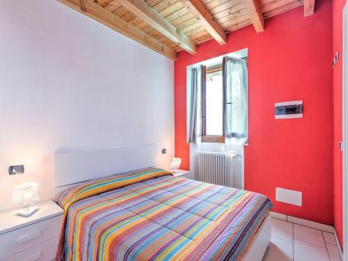 a bedroom with a bed and a red wall at Wonderful flat with swimming pool, lift and garden in Gravedona