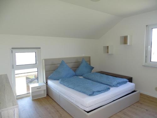 a bed with blue pillows in a white room at Sunny house, 2 residential units in Postmünster
