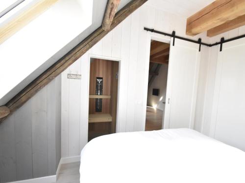 a room with white walls and a staircase with a bed at Studio Hazenborgh in Callantsoog near the sea in Callantsoog
