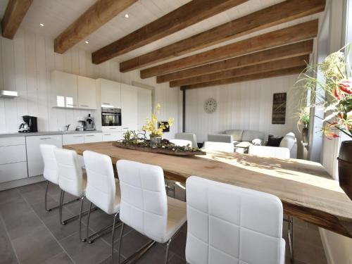 a kitchen with a large wooden table and white chairs at Studio Hazenborgh in Callantsoog near the sea in Callantsoog