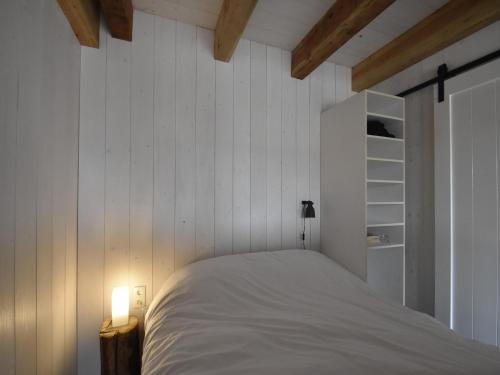 a bedroom with white walls and a bed with a lamp at Studio Hazenborgh in Callantsoog near the sea in Callantsoog