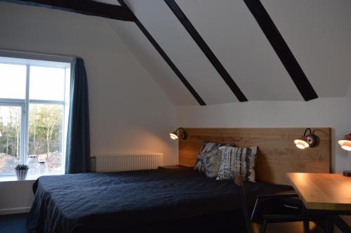 a bedroom with a bed and a table and a window at Femhøj in Jægerspris