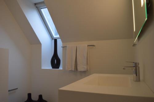 baño blanco con lavabo y ventana en Femhøj en Jægerspris