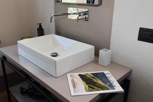 a white sink on a counter with a magazine at The Monteleone Umbria Retreat in Monteleone dʼOrvieto