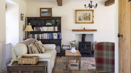 a living room with a white couch and a fireplace at Old Mill Cottage in Kelso