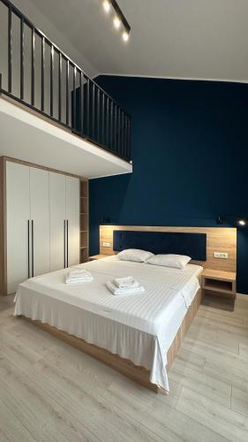 a bedroom with a large bed with a blue wall at ELIZA Apartments - powered by NEO - private parking in Timişoara