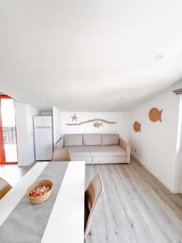 a white living room with a couch and a table at Casa Romeo - Sea View Apartment in Focene