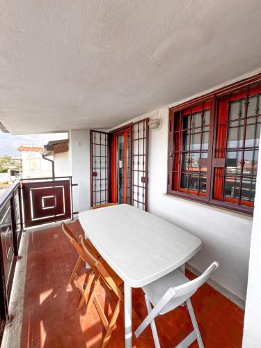 a white table and chairs in a room with windows at Casa Romeo - Sea View Apartment in Focene