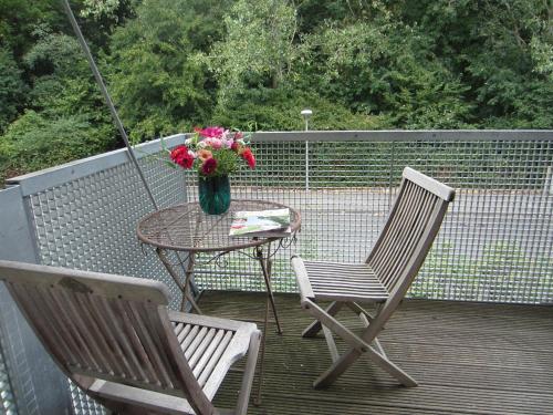 two chairs and a table with a vase of flowers on a deck at K9 Wohnungen in Münster