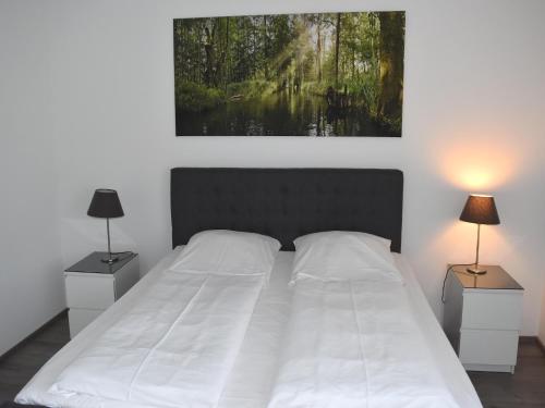 una camera da letto con un grande letto bianco con due lampade di Apartment in Lübben near the water a Lübben