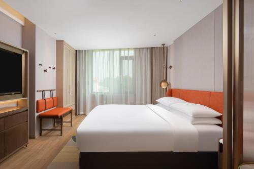 a hotel room with a bed and a flat screen tv at Home2 Suite by Hilton Xishuangbanna Jinghong in Jinghong