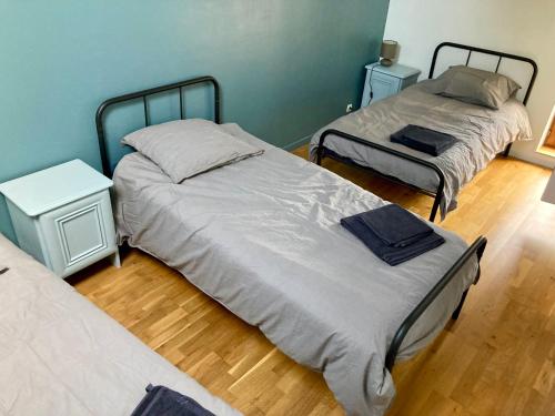 two twin beds in a room with wooden floors at L'Auberge des Clés in Chevannes