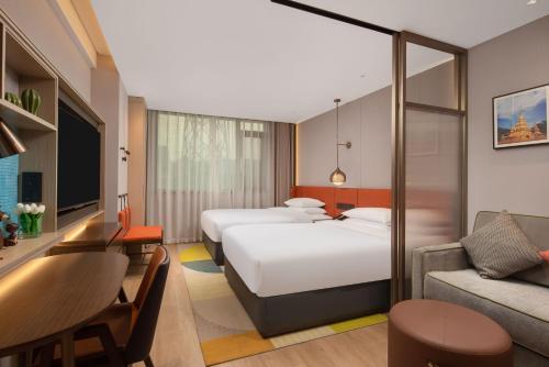a hotel room with two beds and a couch at Home2 Suite by Hilton Xishuangbanna Jinghong in Jinghong