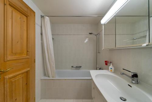 a bathroom with a sink and a tub and a mirror at Chesa Foulla Rosa - 6 pax in Celerina