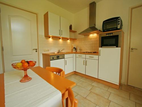 a kitchen with white cabinets and a table with a bowl of fruit at Wijlre Farmhouse stay in Wijlre