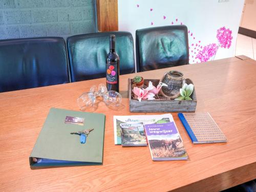 a table with a bottle of wine and a book at Serene Holiday Home in Ulestraten with Terrace in Ulestraten