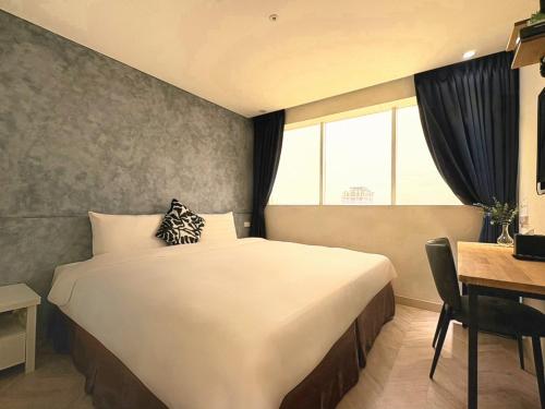 a bedroom with a bed and a desk and a window at Wemeet Hotel Taipei in Taipei