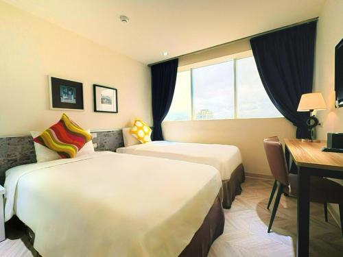 a hotel room with two beds and a desk at Wemeet Hotel Taipei in Taipei
