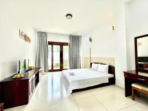 a bedroom with a bed and a desk and a television at RESORT HAVANA Mũi Né in Mui Ne