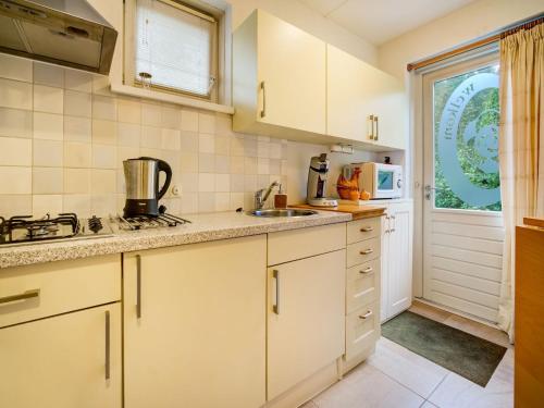 a kitchen with white cabinets and a sink and a window at Homely Apartment in Noordwolde with Balcony in Noordwolde