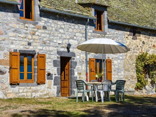 a table and chairs with an umbrella in front of a building at Peaceful Mountain Retreat in Neuvéglise