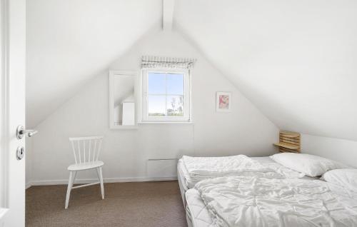 a white bedroom with a bed and a chair at Nice Home In Brenderup Fyn With Sauna in Bro
