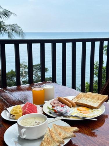 uma mesa com alimentos e bebidas para café da manhã em uma varanda em Chang Cliff Resort em Ko Chang