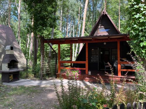 a small cabin with a fireplace in the woods at Domek pod świerkami 2 in Skorzęcin