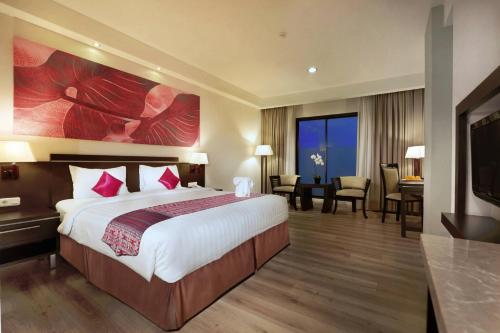 a hotel room with a large bed and a desk at Aston Pontianak Hotel and Convention Center in Pontianak