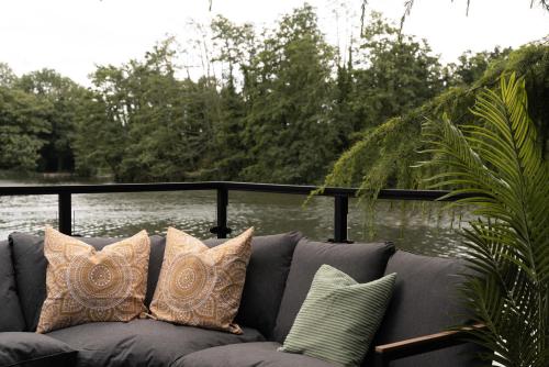 a gray couch with pillows sitting next to a body of water at AvantGlamp in Marston Green