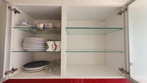 a white cabinet with glass shelves and plates at Magnifique vue mer et terrasse Garage Clim WiFi - ROSSIconciergerie - Linge inclus in La Grande-Motte