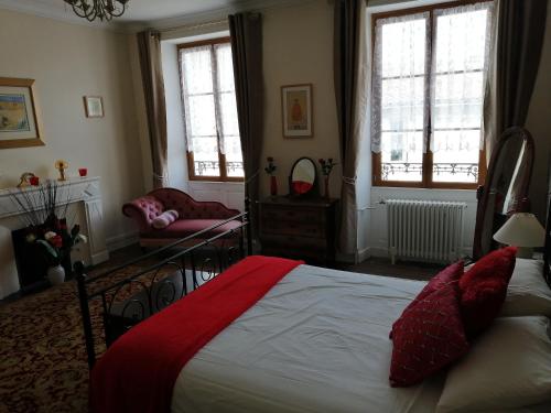 a bedroom with a bed and a chair and windows at Vingt Grand Rue in Champagne-Mouton