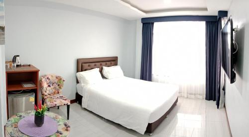 a bedroom with a bed and a chair and a window at La Capannina Hotel Patong in Patong Beach