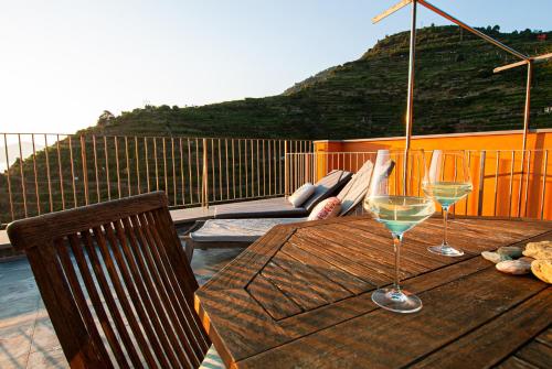 a wooden table with two wine glasses on a balcony at Luxury Seaview Apartments Manarola by Arbaspàa in Manarola