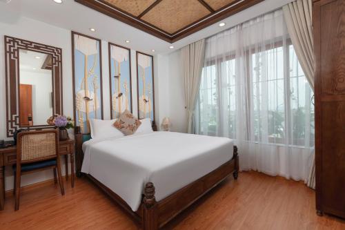 a bedroom with a large white bed and a mirror at Veshia Hotel & Spa in Hanoi