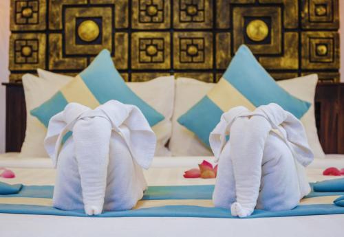 two towel elephants are sitting on a bed at Angkor Land House in Phumĭ Réach Born