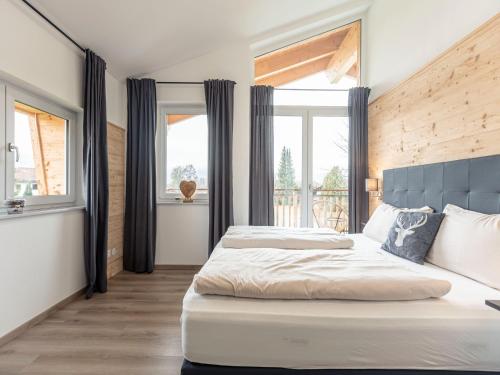1 dormitorio con 1 cama con cabecero azul y ventanas en Inzell Chalets with private pool, en Inzell