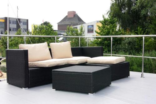 a wicker couch and stool on a balcony at Houseboat Leni, Flensburg in Flensburg
