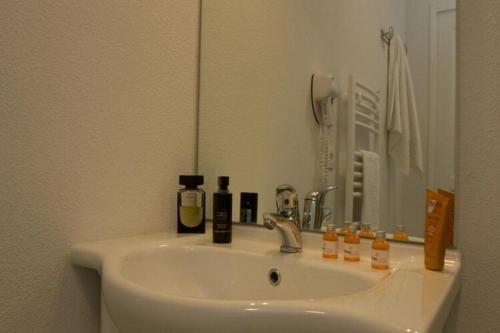 a bathroom with a sink with a mirror and bottles on it at Residence Les Isles de Sola, Grandcamp, Studio in Grandcamp-Maisy