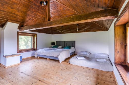 two beds in a room with a wooden ceiling at Imperial Apartments - Villa Koleczkowo in Koleczkowo
