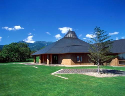 a house with a roof with a tree in the yard at Yatsugatake Kogen Lodge in Minamimaki