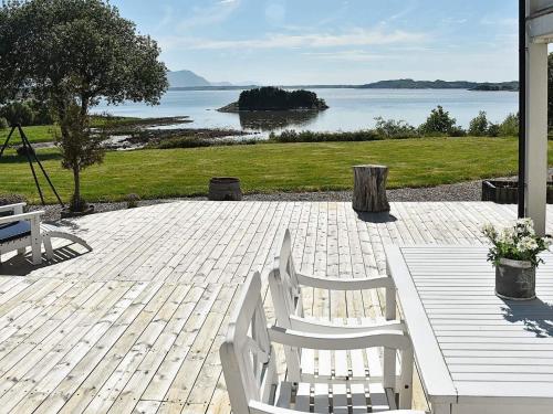 a patio with two white chairs and a table and water at 10 person holiday home in Tornes I Romsdal in Tornes