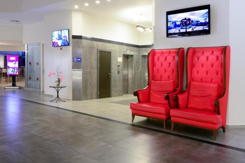 a room with two red chairs and a tv at Leonardo Club Tiberias - All Inclusive in Tiberias